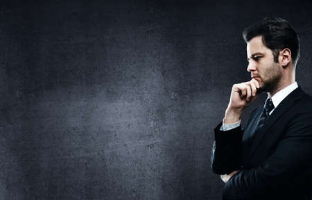 businessman thinking on a gray concrete wall backgroundの写真素材