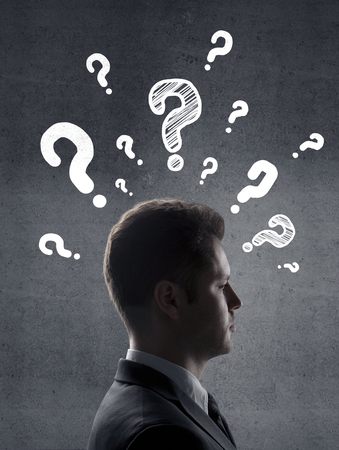 man with questions symbol on gray wall backgroundの写真素材