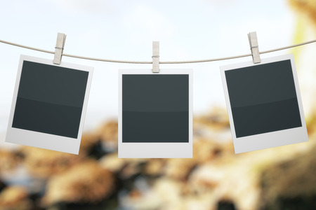 Three blank photo hanging on rope with clothespins on landscape background. Mock up, 3D Renderの写真素材