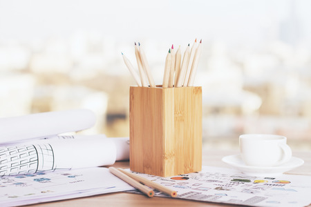 Wooden pencil holder and coffee cup on desktop with sketchesの写真素材