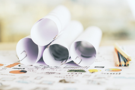 Desktop with paper rolls on sketched charts and diagramsの写真素材