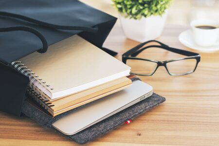 Wooden desktop with glasses, notepads, coffee and other itemsの写真素材