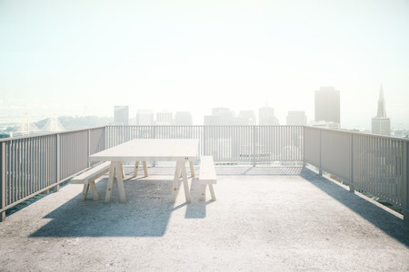 Balcony design with table and benches, concrete floor and railing on sunlit city background. 3D Renderingの写真素材
