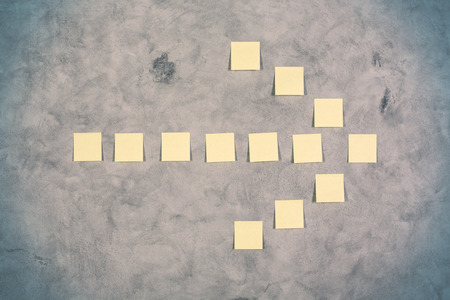 Yellow paper sticker arrow on concrete wallの写真素材