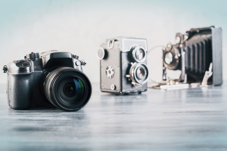 Three different cameras on grey wooden desktop