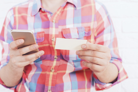 Man holding business card and dialing number on his smartphoneの写真素材