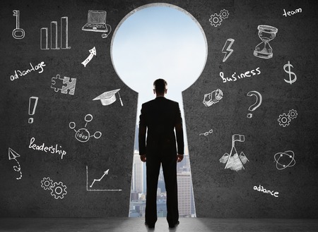 businessman standing and looking on keyhole, close upの写真素材