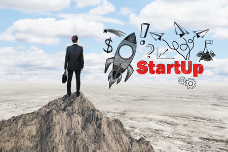 Start up concept with rocket ship sketch and businessman looking at desert from mountain topの写真素材