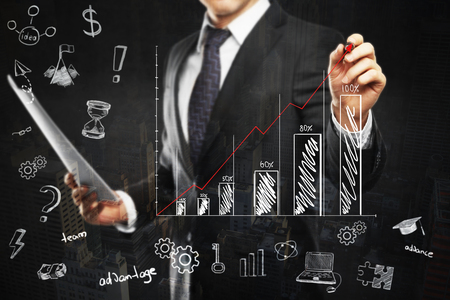 Financial growth concept with businessman holding document and drawing abstract business chart on dark backgroundの写真素材