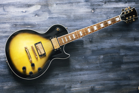 Top view of black and yellow electric guitar on dark wooden surfaceの写真素材
