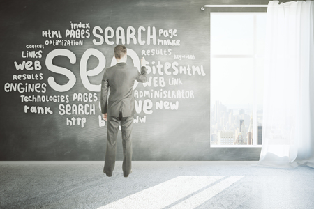 Search engine optimization concept with businessman writing on chalkboard wall in room with concrete floor, window with curtain and city view. 3D Renderingの写真素材