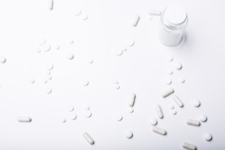 Top view of bright desktop with white pills, cupsules and prescription bottle