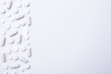 Blank bright surface with white pills and capsules on the left. Mock upの写真素材