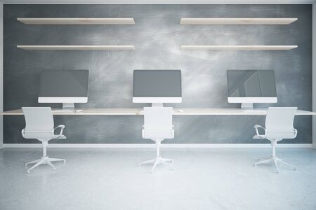 Coworking office interior with three blank computer monitors, table, chairs and shelves on...