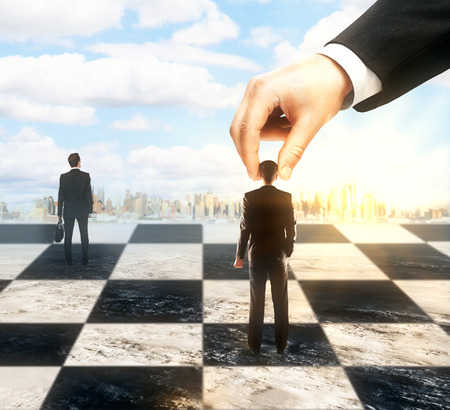Strategic planning and control concept with hand moving businesspeople on chessboard. City and sky backgroundの写真素材