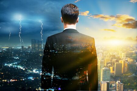 Research concept with back view of businessman looking into the distance on stormy and sunny city background. Double exposureの写真素材