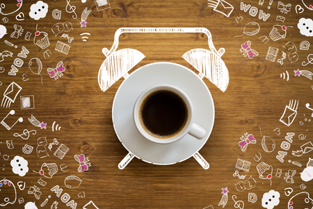 Coffee cup alarm clock sketch on wooden desktop with communication drawingsの写真素材