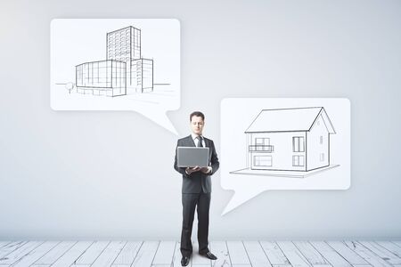 Young architect with laptop standing near abstract speech bubbles with construction sketchesの写真素材