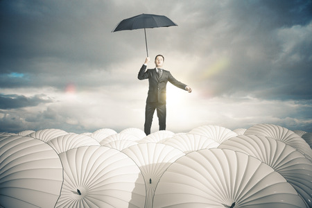 Businessperson with white umbrellas on stormy sky background. Business protection concept. 3D Renderingの写真素材