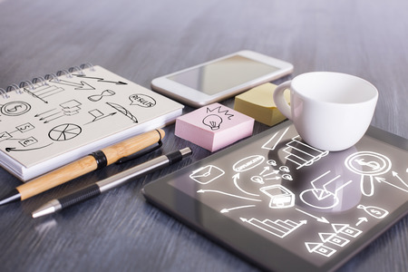 Closeup of wooden office desktop with business sketches on electronic devices and supplies