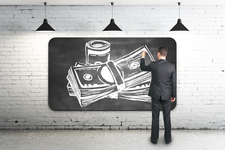 Businessman drawing creative money sketch on chalkboard in white brick interior. 3D Renderingの写真素材