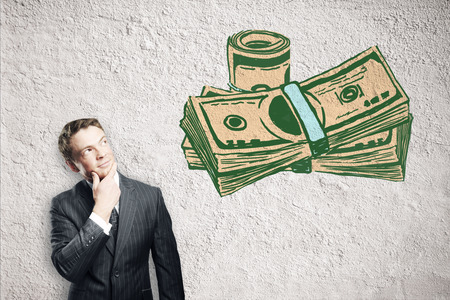 Thoughtful young businessman looking at creative dollar banknote drawing on concrete background. Financial growth conceptの写真素材