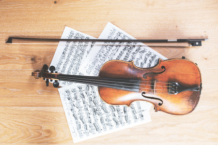 Violin, bow and music sheets placed on light wooden floor. Concert rehearsal conceptの写真素材