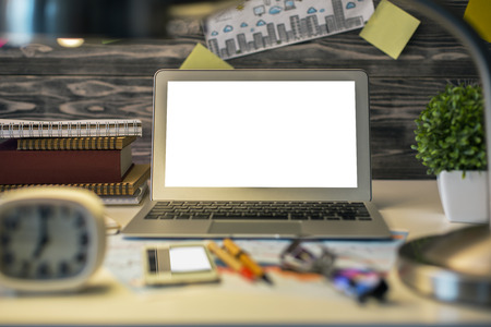 Close up of creative desktop with white laptop screen and other blurry items. Mock up