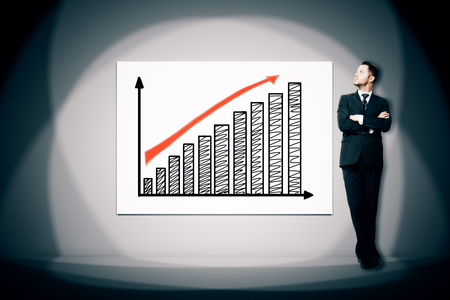 Businessman looking at business chart illuminated with spot light. Success conceptの写真素材