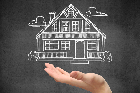 Hand holding creative house sketch on textured concrete wall background. Real estate conceptの写真素材