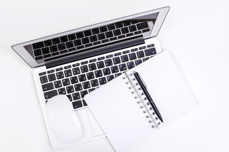 Top view of white desktop with laptop, empty notepad and computer mouse. Mock up