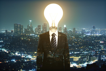 Abstract light bulb headed businessman on night city background. Idea concept. Multiexposureの写真素材