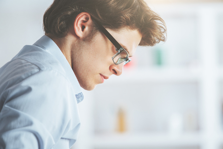 Side portrait of attractive young man in glasses on blurry backgroundの写真素材