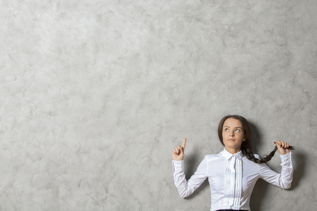 Portrait of pretty european businesswoman on textured concrete wall background with copy spaceの写真素材