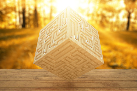 Abstract light wooden cube with engraved maze on autumn forest background. 3D Renderingの写真素材