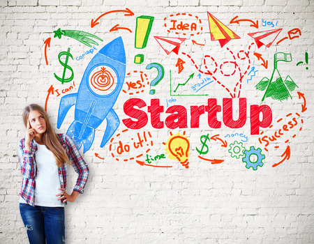 Thinking caucasian girl with creative startup sketch on white brick background. Start up conceptの写真素材