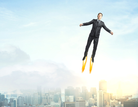 Young man flying in sky with copy space above cityの写真素材