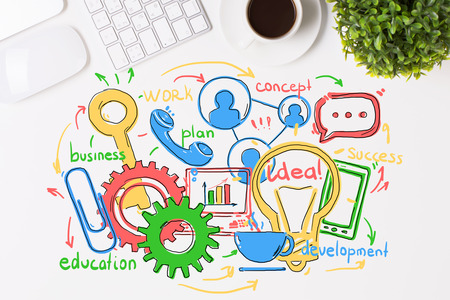 Top view of white desktop with colorful business sketch, keyboard, coeffee cup, plant and other itemsの写真素材