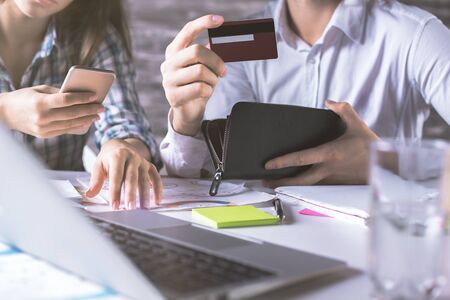 Close up of young business man and woman with credit card, purse, smartphone and laptop. Online...