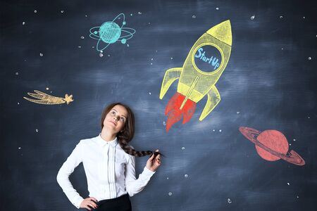 Thoughtful caucasian girl on chalkboard background with creative rocket ship sketch. Start up...