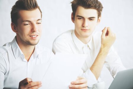 Two handsome young european males doing paperwork in modern officeの写真素材