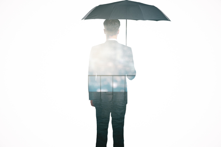 Back view of businessman with umbrella standing on balcony. Double exposure. Protection conceptの写真素材
