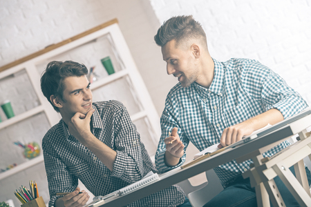 Two attractive caucasian businessmen doing paperwork in modern bright officeの写真素材