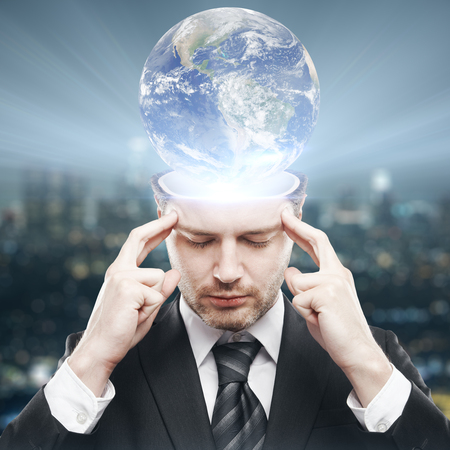 Thoughtful young businessman with abstract globe brain. Global thinking concept.の写真素材
