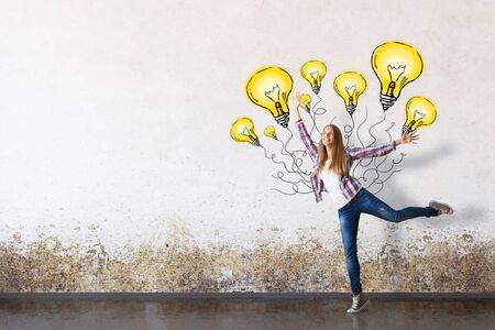 Happy girl dancing with abstract light bulb balloons in concrete rooms. Successful ideasの写真素材
