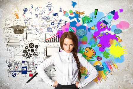 Confident young female on concrete background with mathematical formulas and colorful drawings. Creative and analytical thinking conceptの写真素材