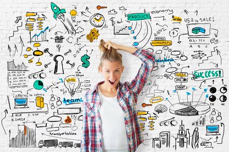 Crazy smiling girl pulling her hair on brick background with colorful business sketch