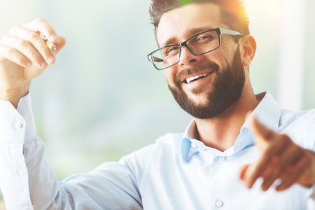 Close up portrait of smiling young man pointing at cameraの写真素材