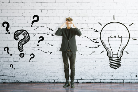 Thoughtful man with drawn question marks and lamp on brick background. Idea conceptの写真素材