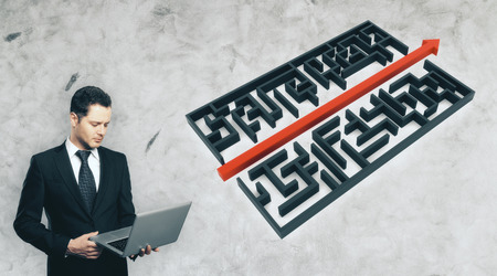 Businessman using laptop next to abstract maze with arrow on concrete background. Problem solution...